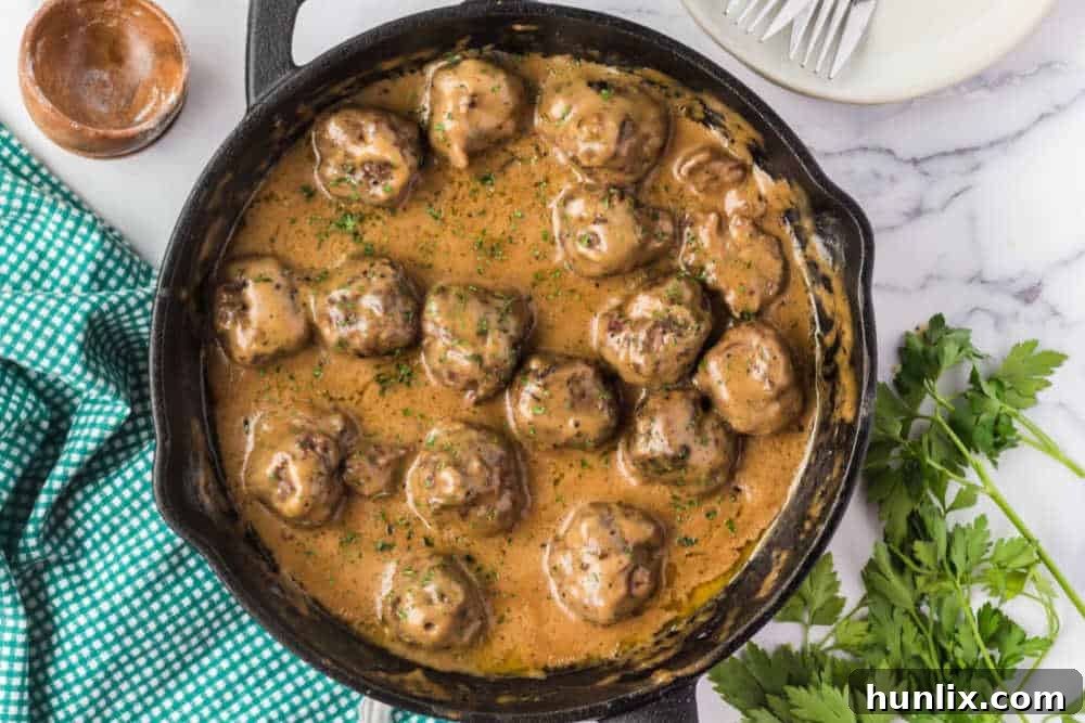 Traditional Swedish Meatballs 2 Swedish meatballs with sauce in a cast iron skillet, ready to be served.