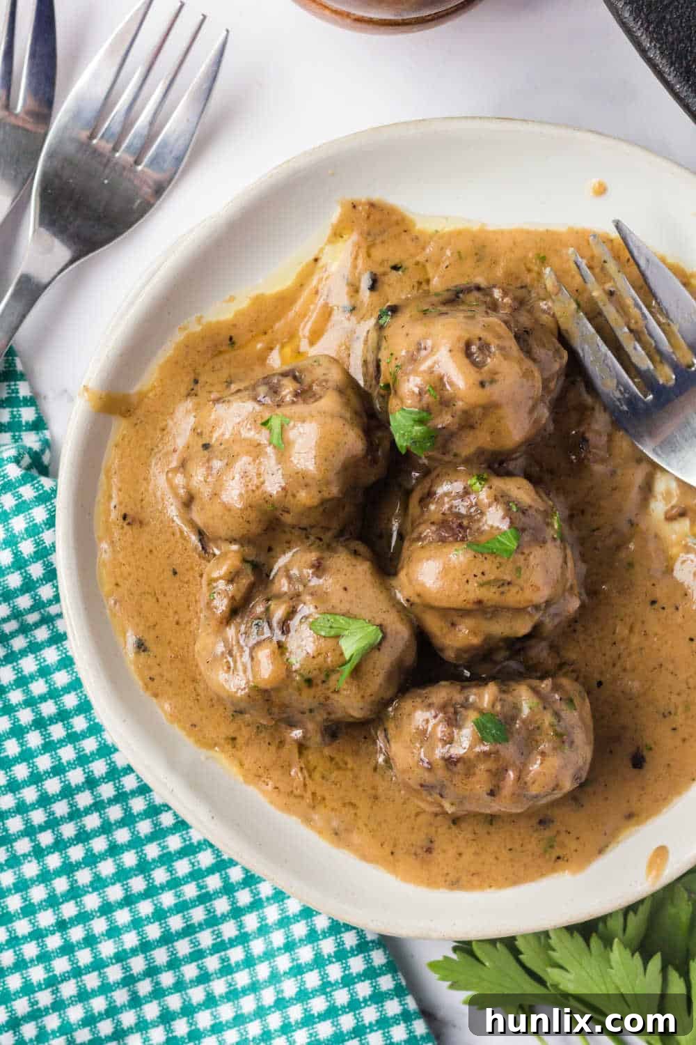 Traditional Swedish Meatballs 10 Plated Swedish meatballs on a white plate with generous amounts of creamy sauce.