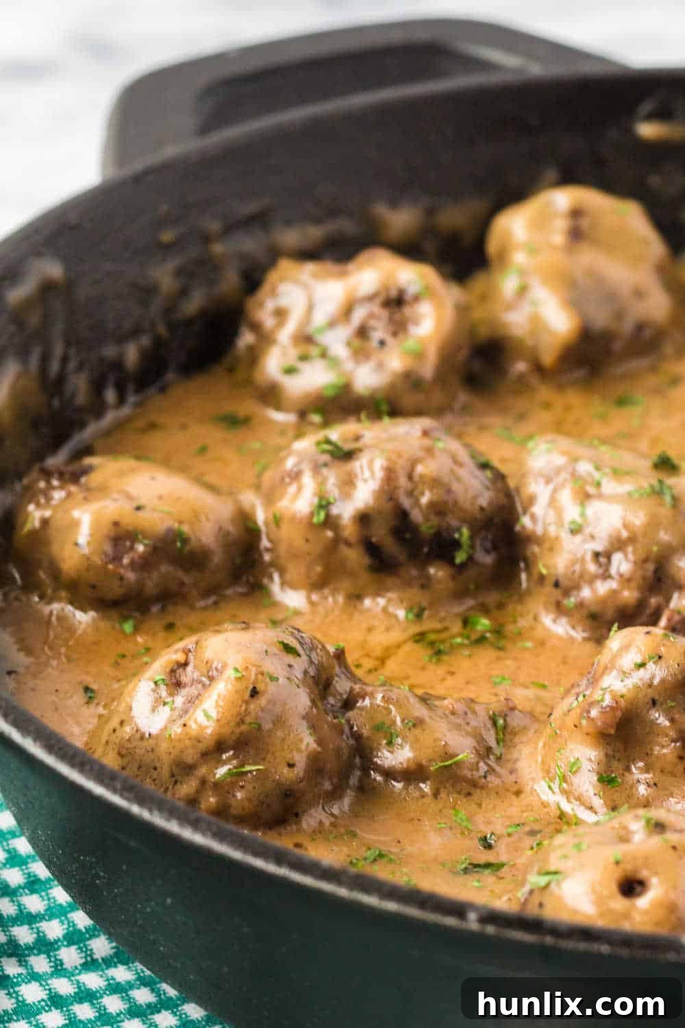 Traditional Swedish Meatballs 7 A cast iron skillet filled with creamy Swedish meatballs and gravy, ready for serving.