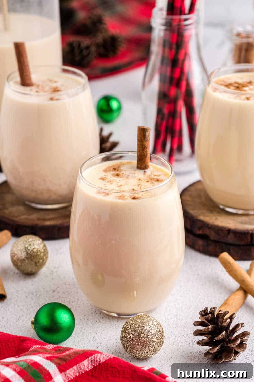 Velvet Spiced Eggnog 7 Glasses of the recipe with Christmas decor on a table.