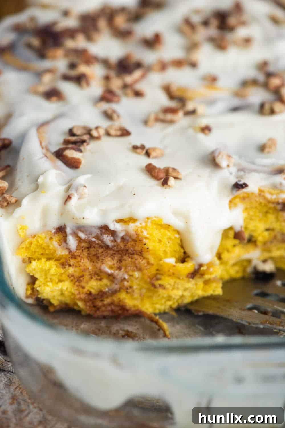 Pumpkin Spice Cinnamon Swirls 9 A close-up of baked pumpkin cinnamon rolls in a casserole pan with generous cream cheese frosting