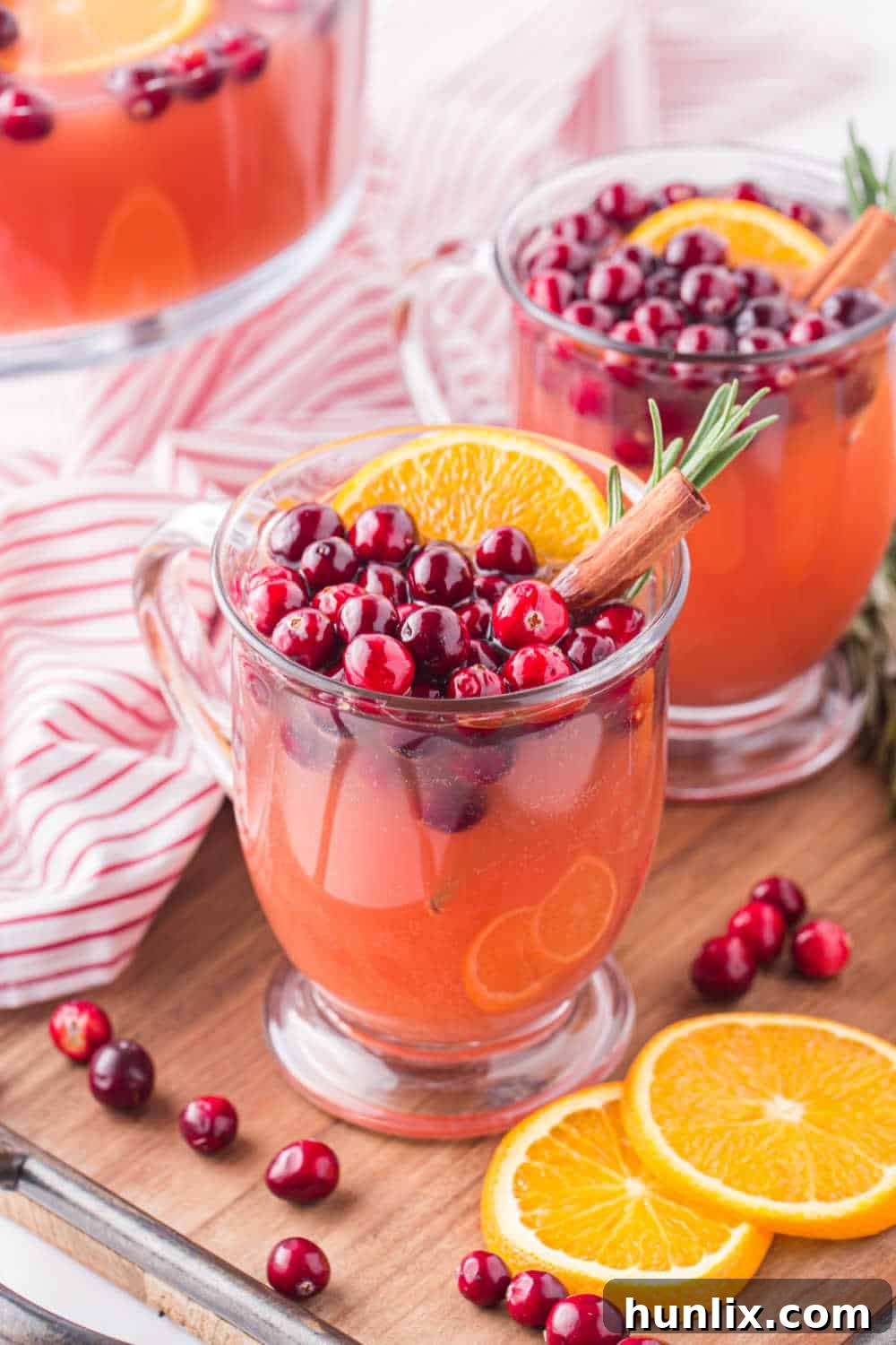 Crimson Spice Elixir 9 Multiple glasses filled with Spiced Cranberry Punch, each expertly garnished with fresh cranberries, orange slices, and cinnamon sticks, arranged artfully for a festive presentation, inviting guests to enjoy.