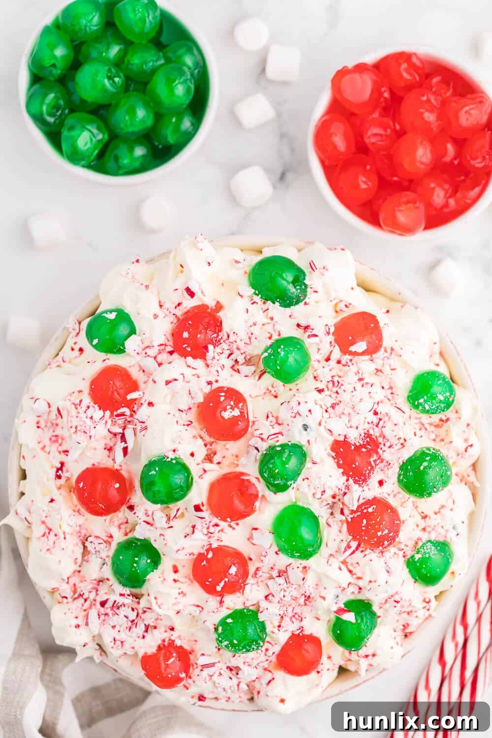A festive bowl of Christmas Fluff dessert salad, adorned with red and green candied cherries, ready to be served during the holiday season.