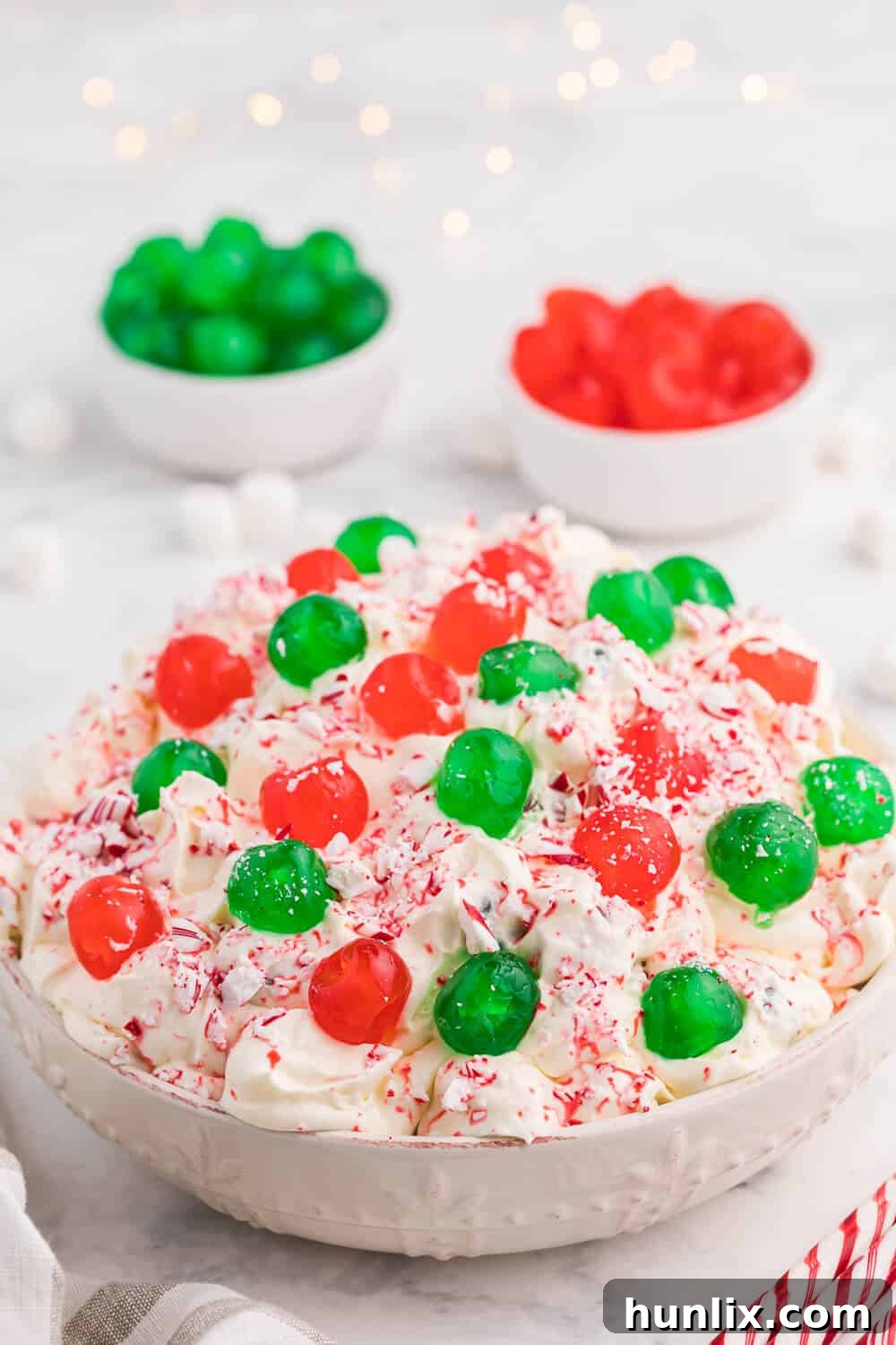 A beautiful serving bowl filled with Christmas Fluff, showcasing its creamy texture, colorful cherries, and hints of white chocolate, ready for a holiday feast.