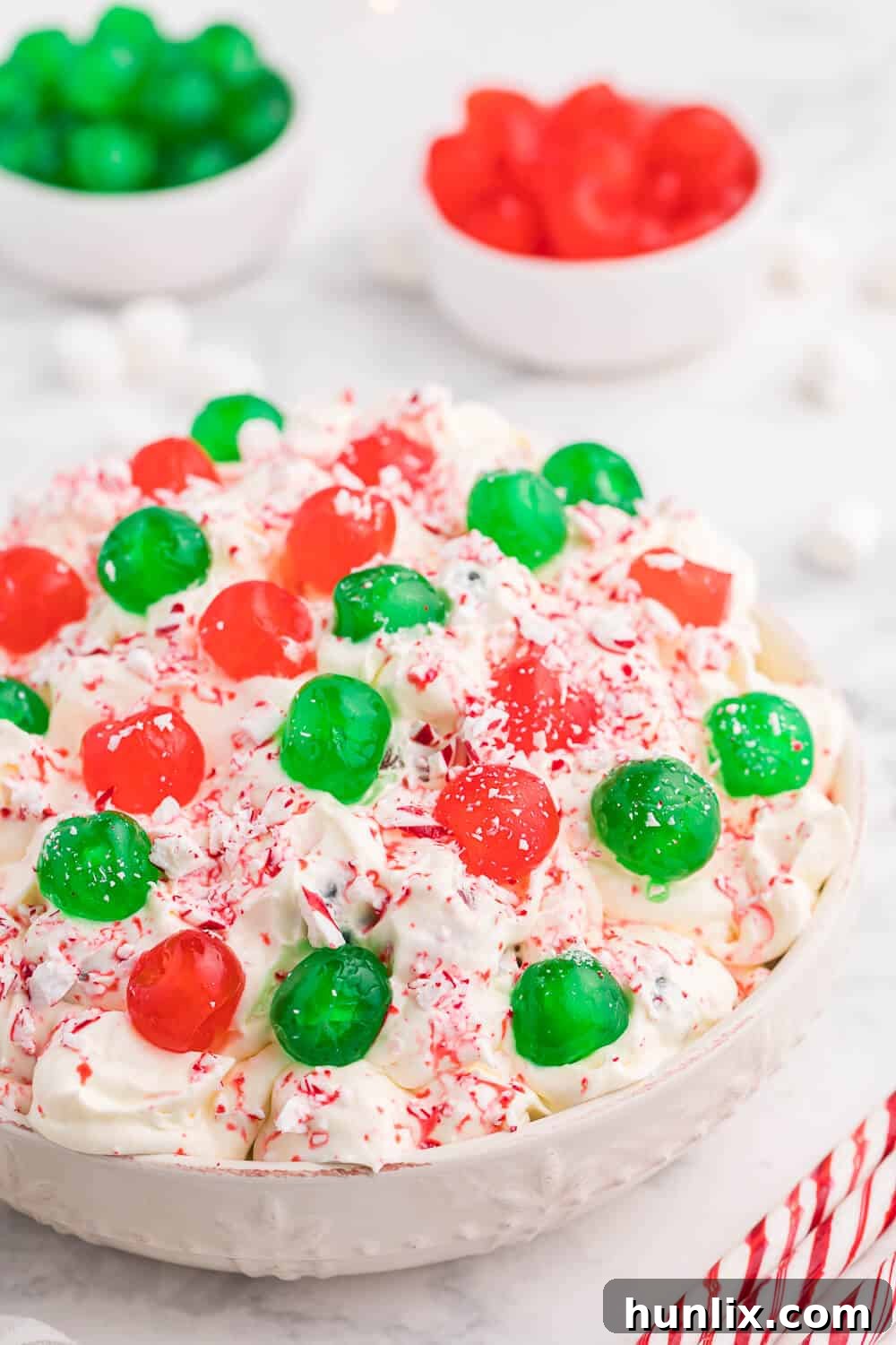 A generous serving of Christmas Fluff in a bowl, showcasing its fluffy texture and the festive colors of red and green cherries, with a smooth, creamy base.