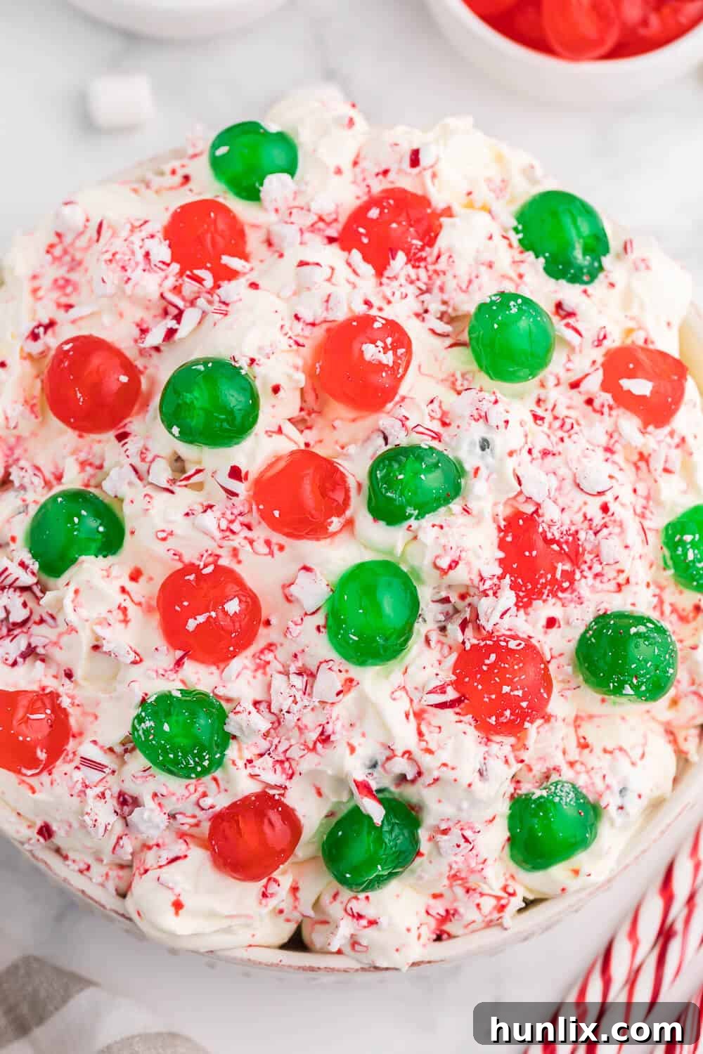 A close-up shot of Christmas Fluff in a serving bowl, highlighting the rich, creamy texture and the vibrant red and green cherries, ready to be enjoyed.