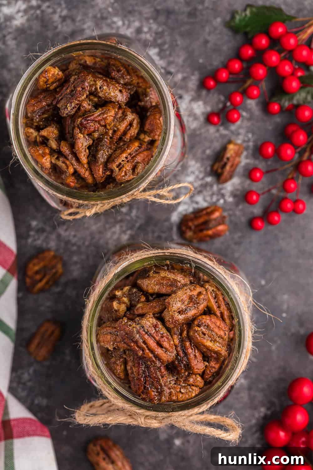 Two jars of air fryer candied pecans with Christmas decor, showcasing their inviting appearance.