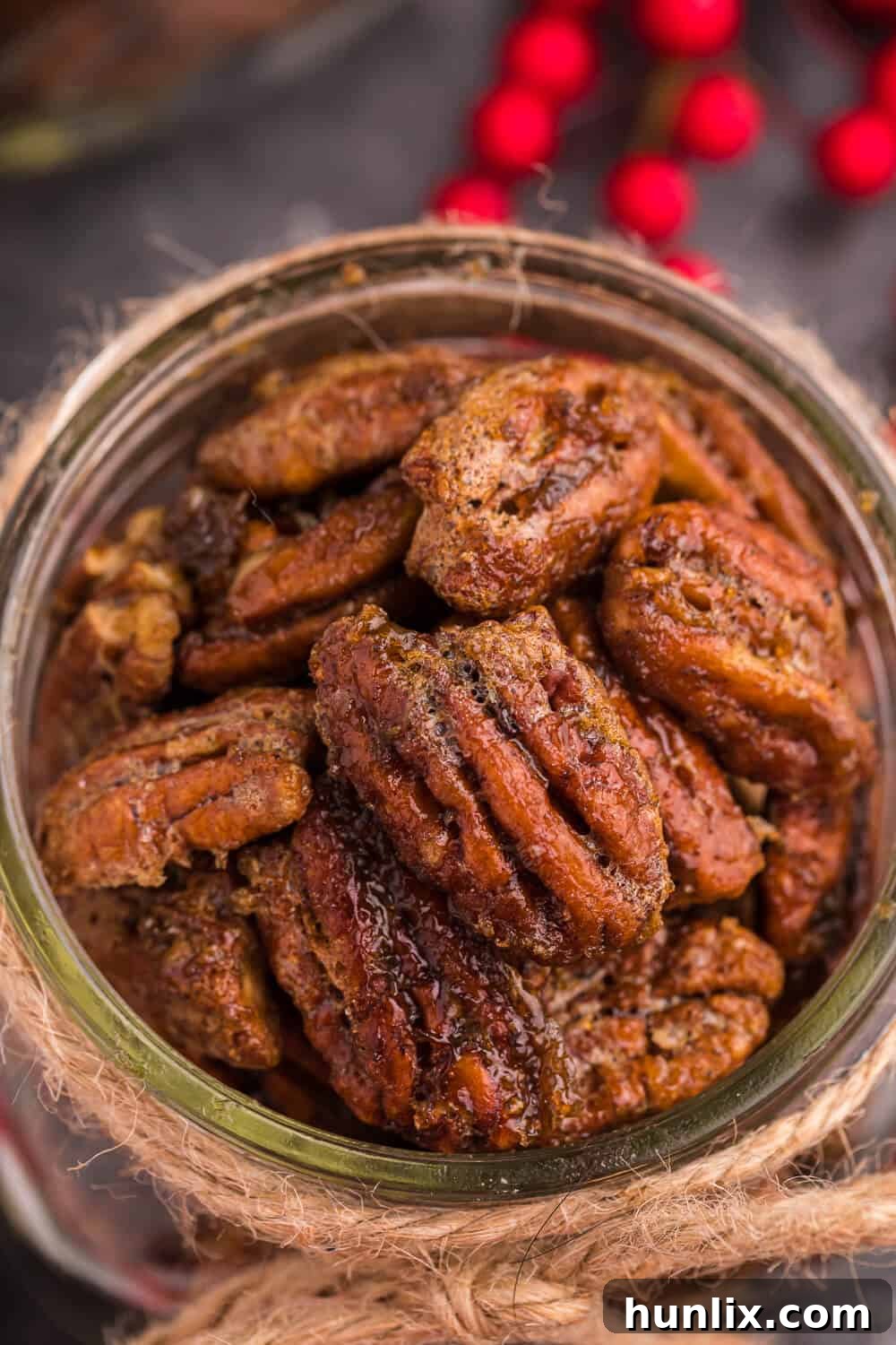 A jar of the air fryer candied pecans, beautifully showcasing the golden, caramelized coating on each nut.