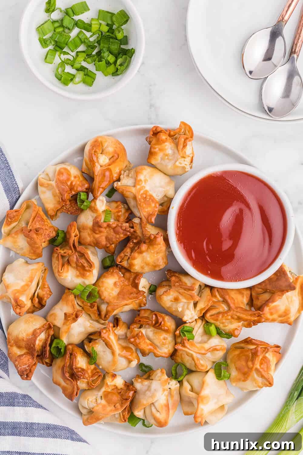 A plate of air fryer crab rangoon with sweet and sour sauce, showcasing their crispy exterior and golden color.