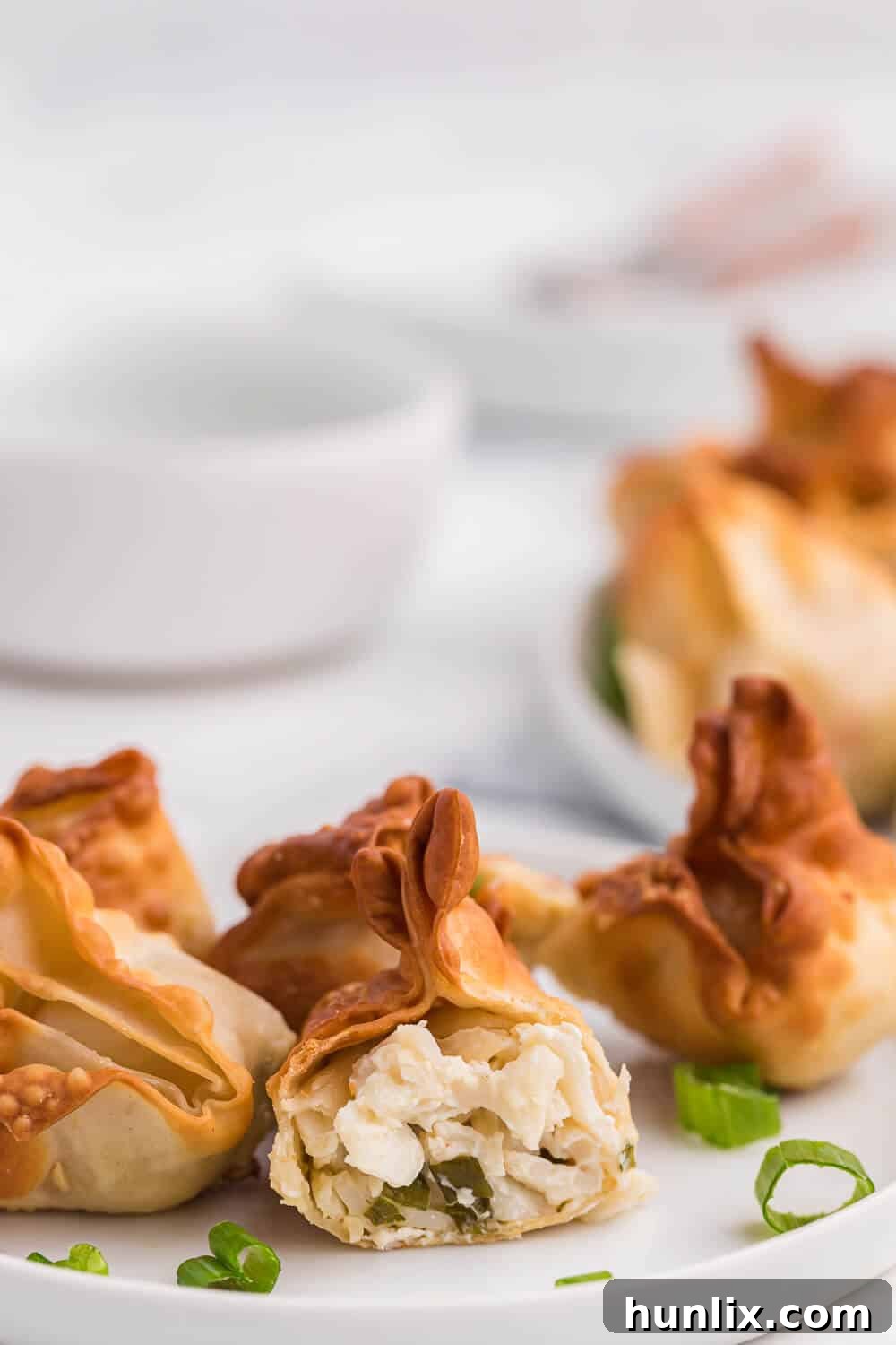 A crispy air fryer crab rangoon cut in half, revealing the creamy crab and cream cheese filling inside.
