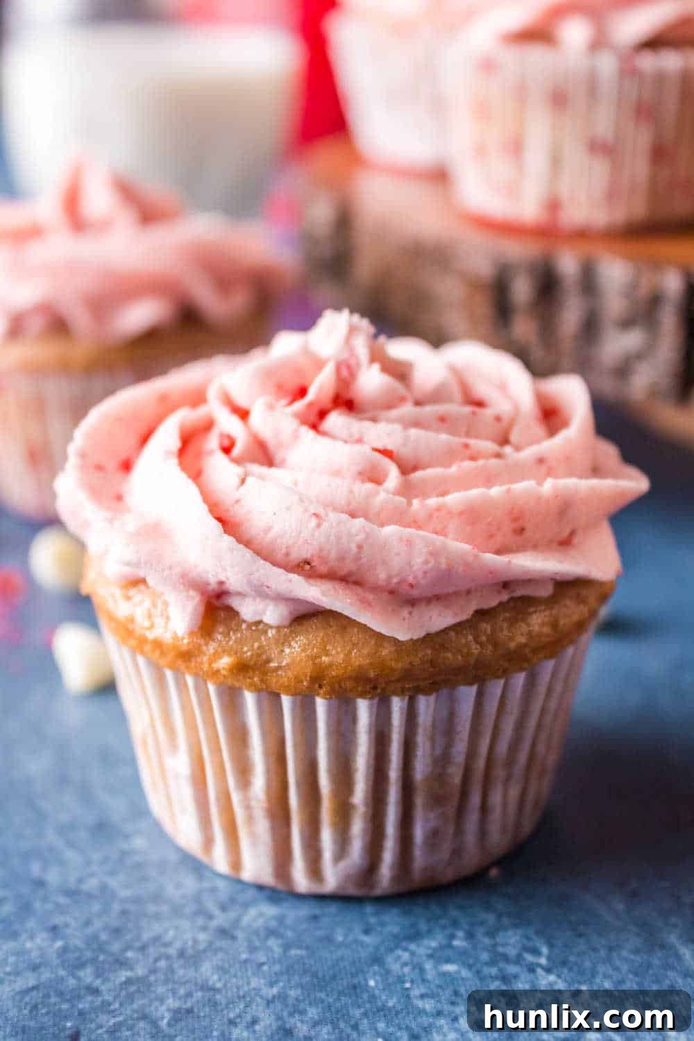 A row of frosted strawberry cupcakes on a blue background, ready to be served.