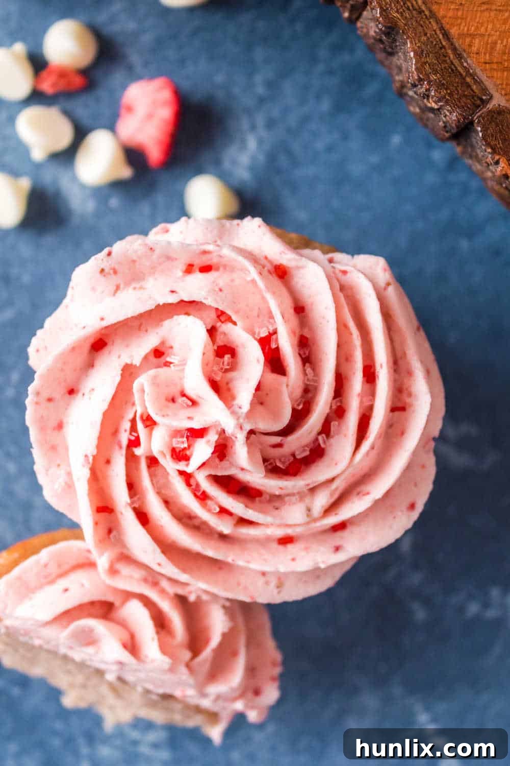 An overhead shot of a perfectly frosted strawberry cupcake, showcasing its vibrant pink frosting and decorations.