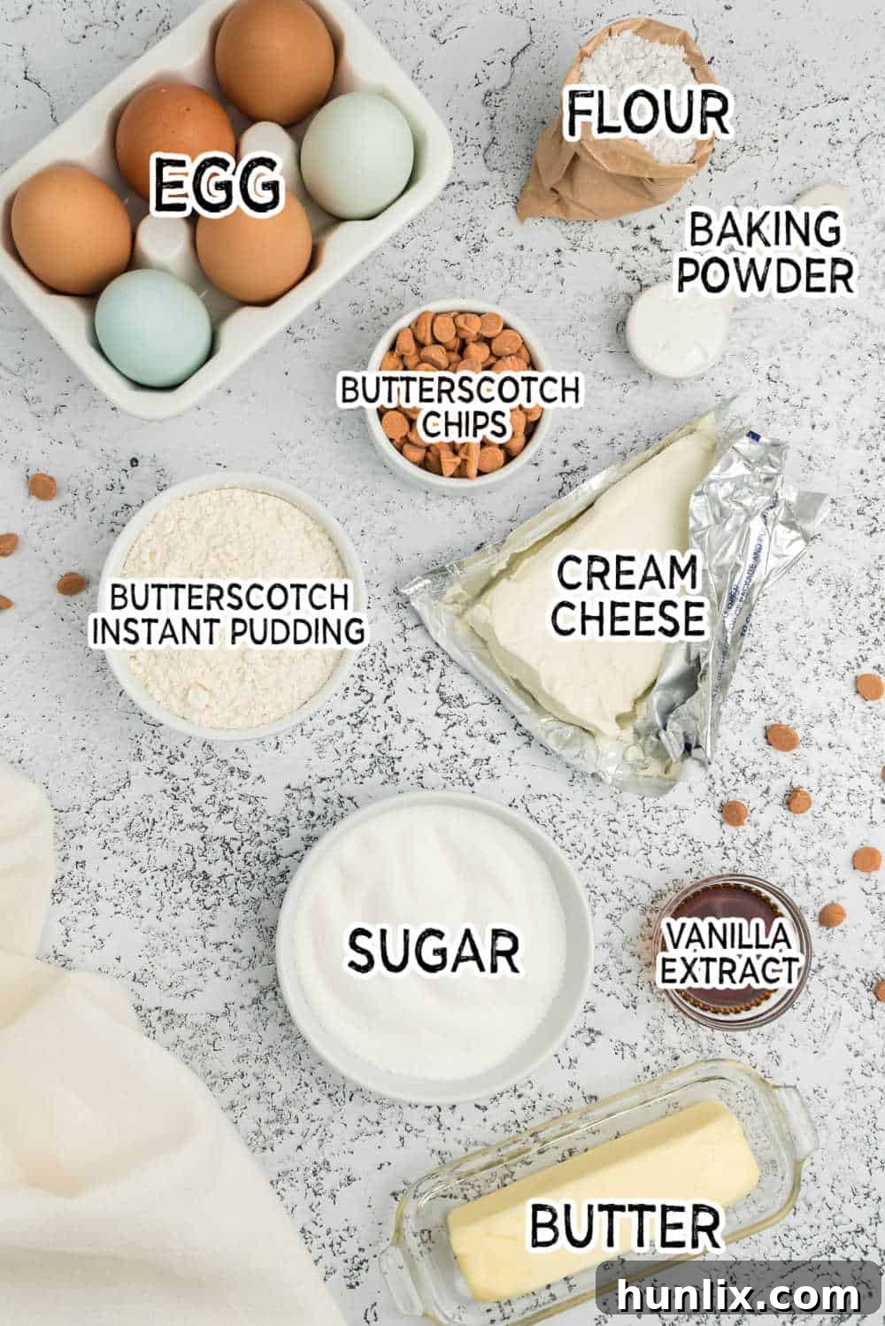 A flat lay of ingredients for butterscotch pudding cookies including flour, butterscotch chips, butter, cream cheese, sugar, and instant pudding mix.