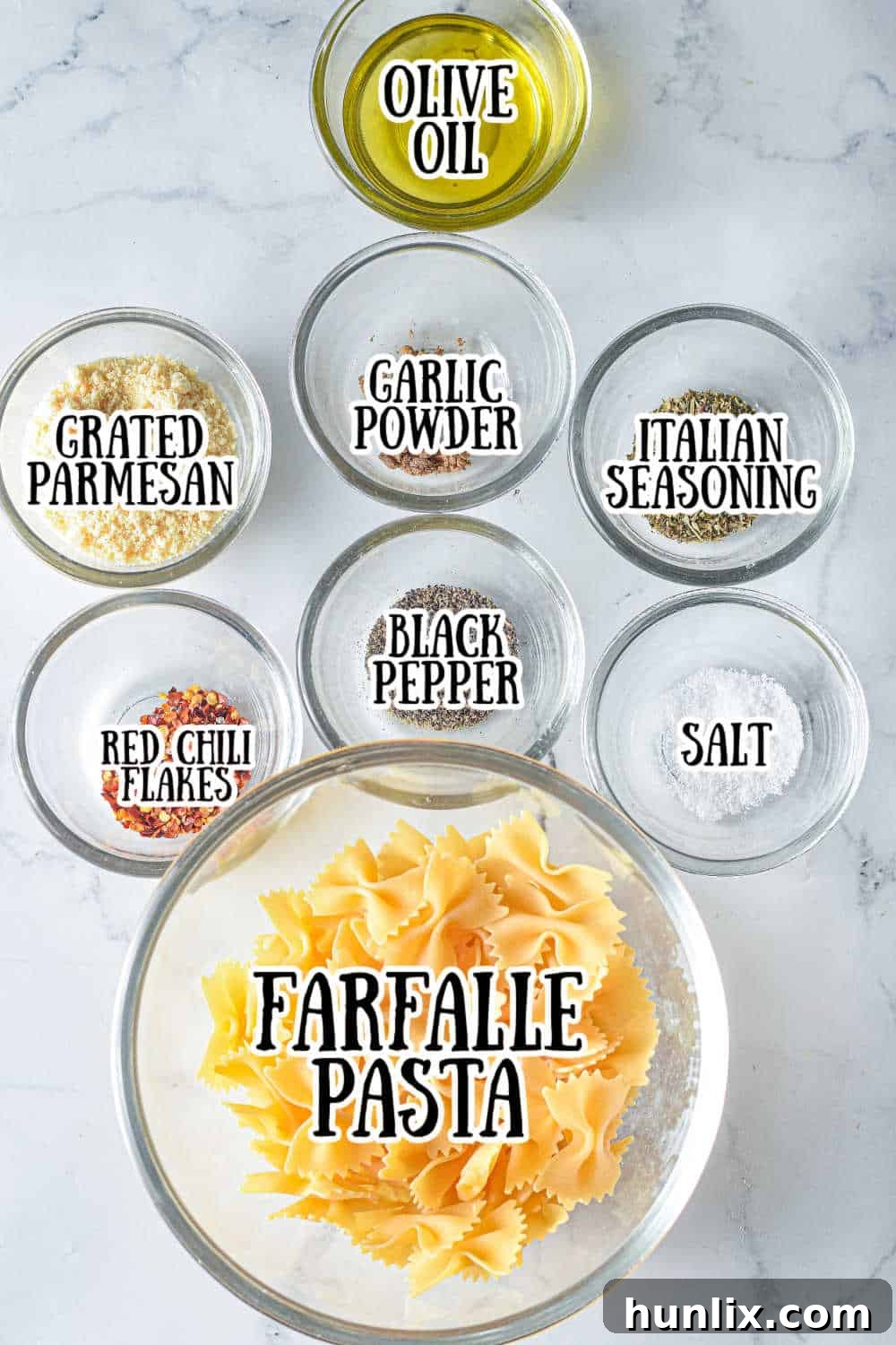 Air Fried Pasta Crisps 3 Ingredients for air fryer pasta chips laid out on a marble counter, including farfalle pasta, olive oil, parmesan, and spices.