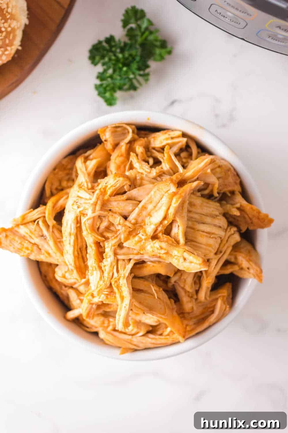 A bowl of Instant Pot BBQ shredded chicken, garnished and ready to be served, highlighting its rich color and tender appearance.