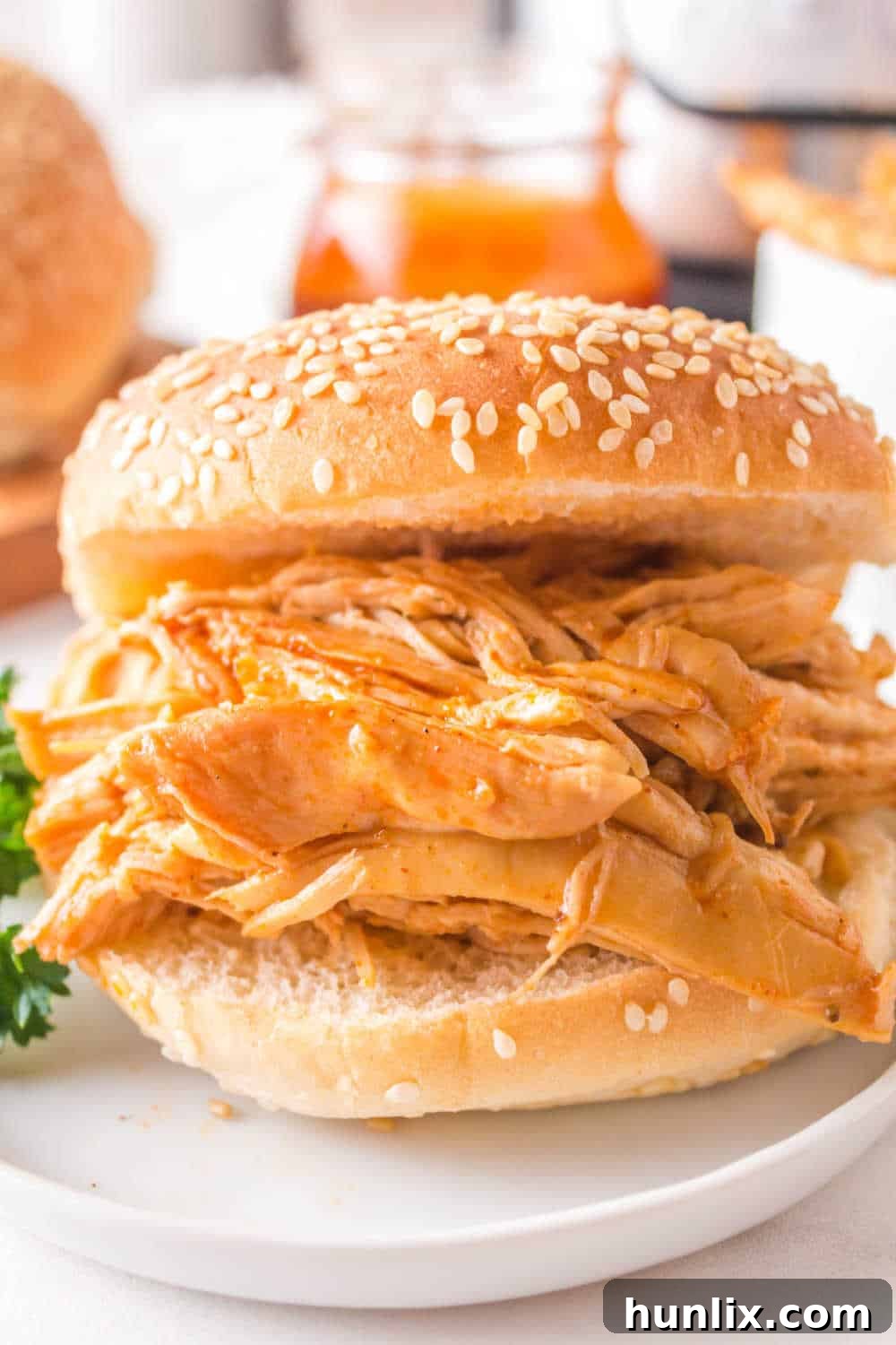 Instant Pot BBQ shredded chicken served on a soft bun with a fresh garnish.