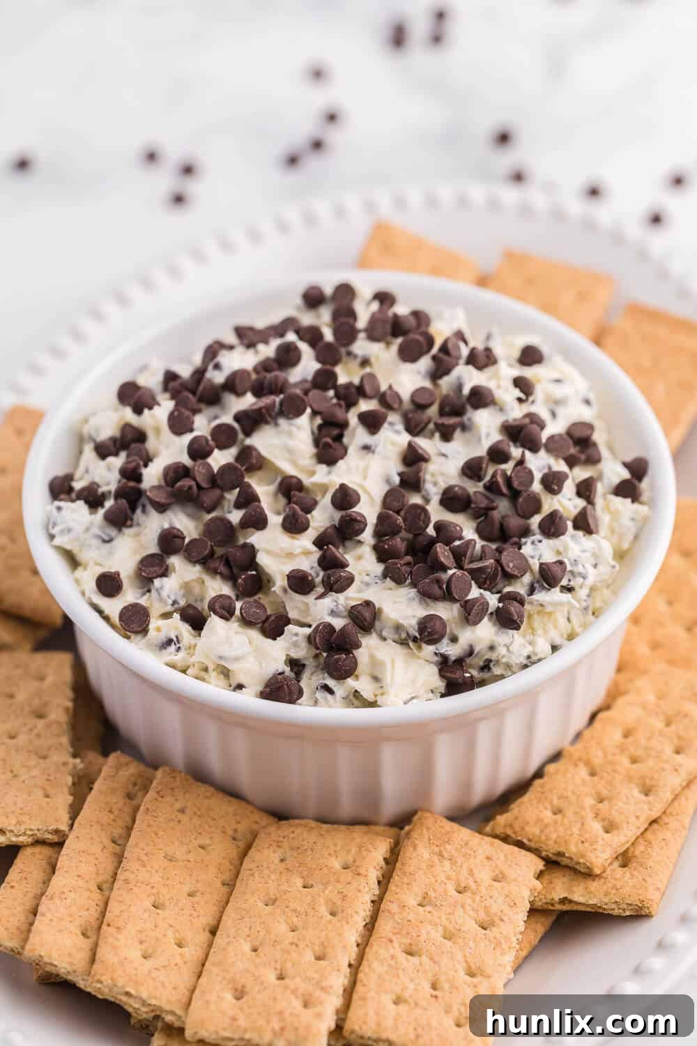 A bowl of Booty Dip artfully arranged with golden brown graham crackers around it, inviting you to dip.