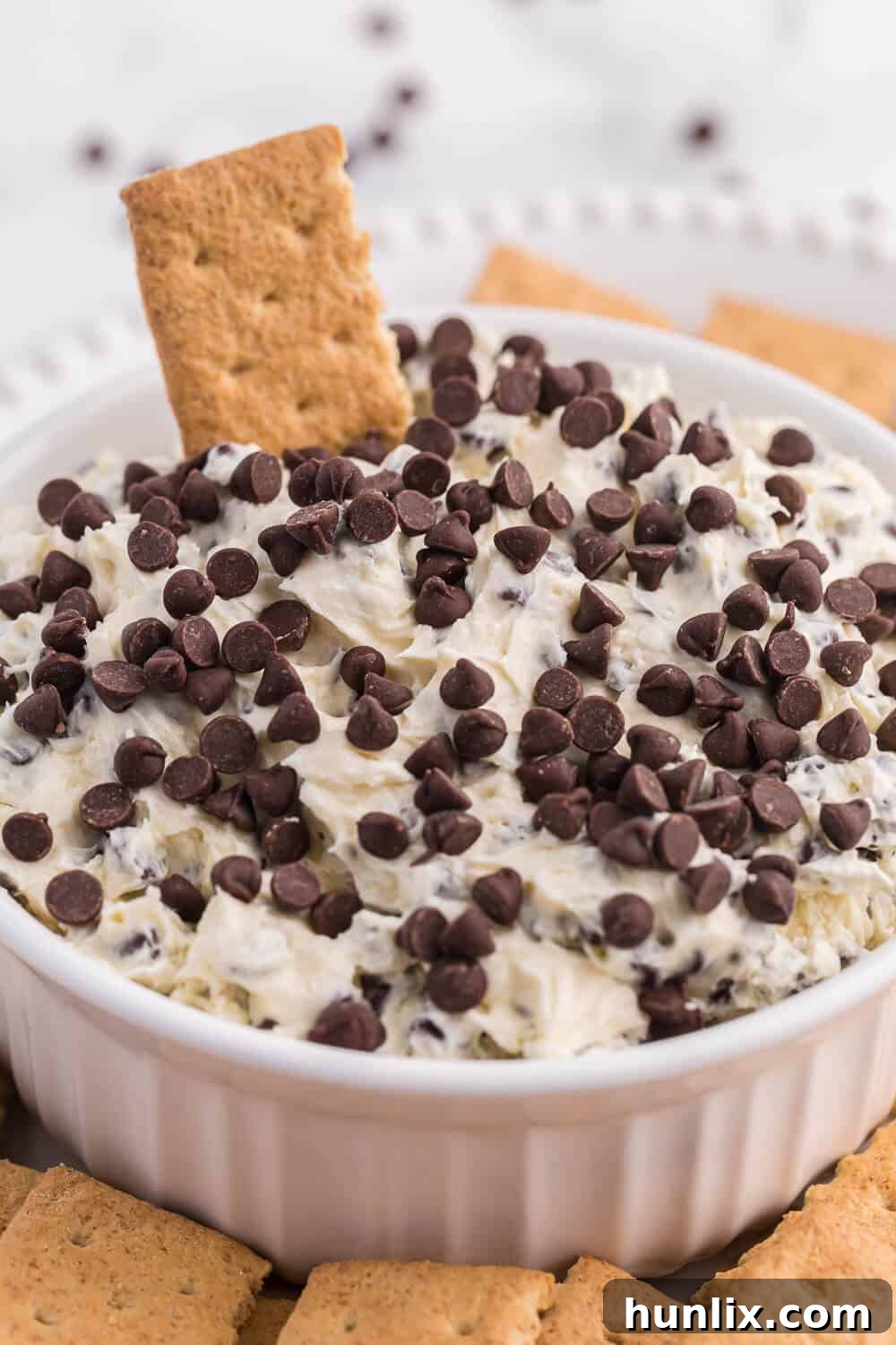 A close-up shot of Booty Dip in a bowl, with a graham cracker dipped in and taking a generous scoop.