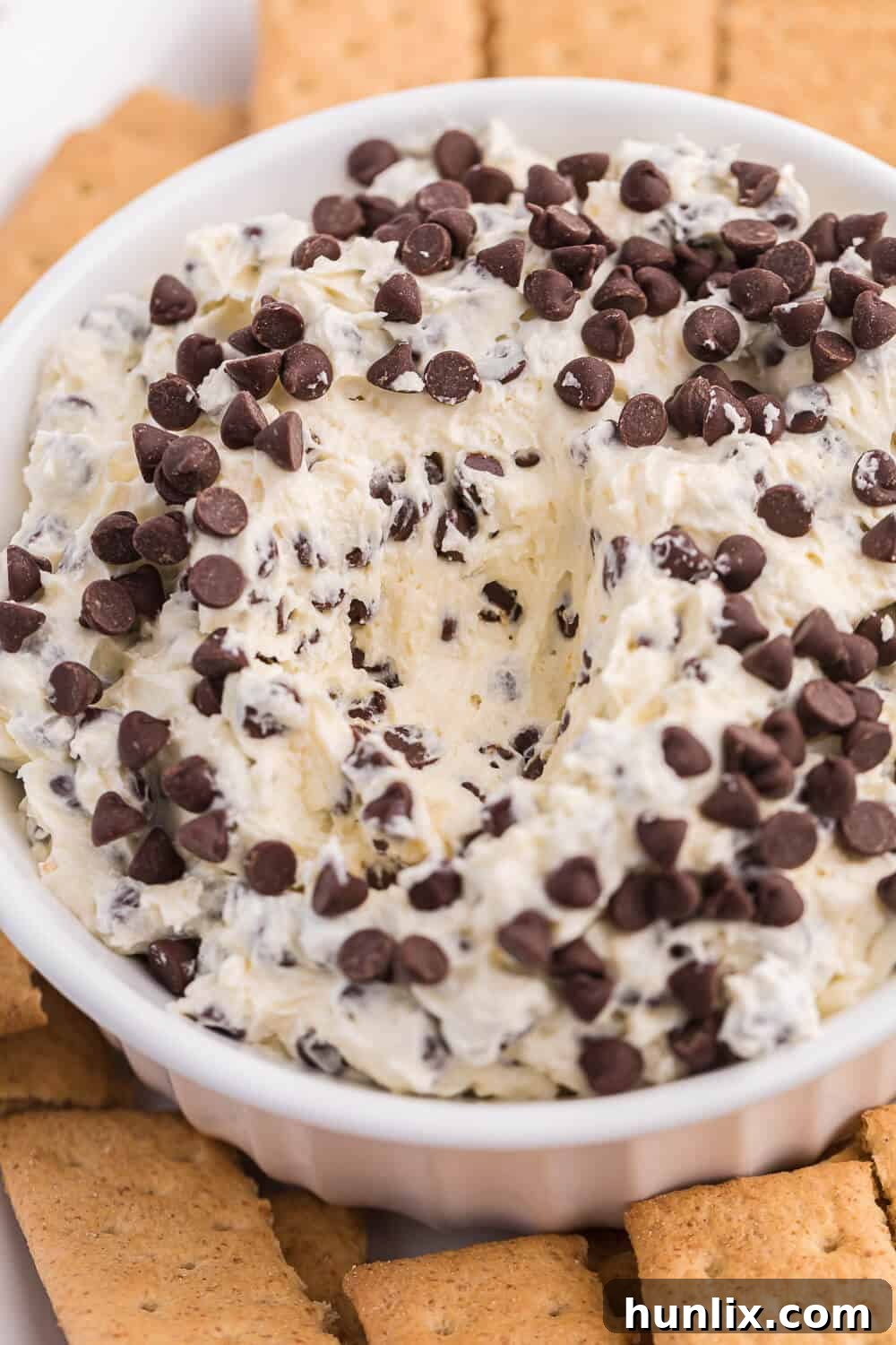 A bowl of Booty Dip with a spoon, showing a generous portion scooped out, surrounded by dippers.