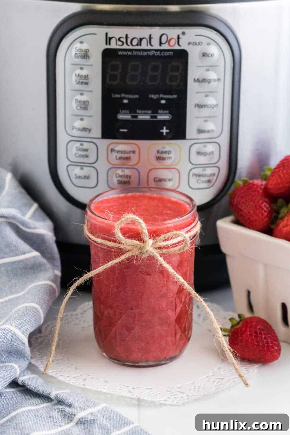 Effortless Instant Pot Strawberry Jam 2 A charming glass jar of freshly made Instant Pot Strawberry Jam, set against the backdrop of an Instant Pot cooker, suggesting easy homemade goodness.