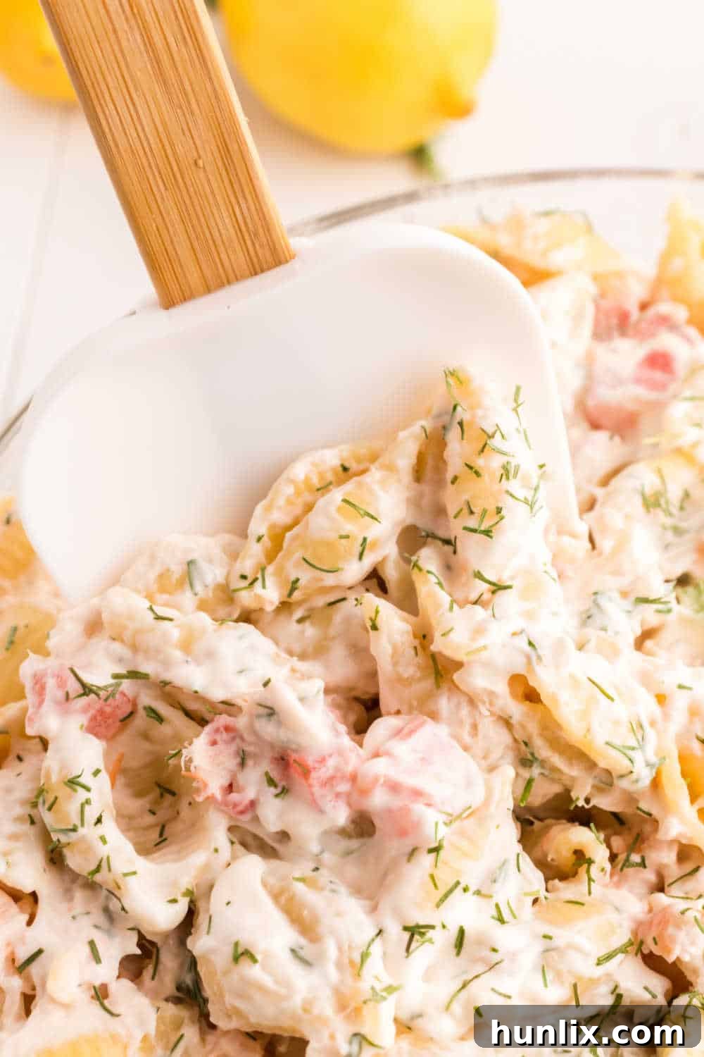 Zesty Shrimp Pasta Salad 9 A close-up shot of creamy shrimp pasta salad in a bowl, with a scraper spatula used to mix, highlighting the texture.