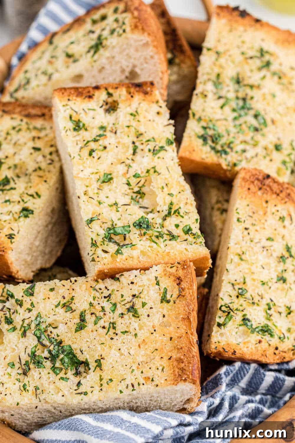 Several golden-brown slices of garlic bread in a brown woven basket, ready to be enjoyed.