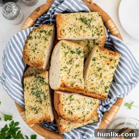 Slices of freshly baked garlic bread, arranged neatly in a rustic woven basket, ready to be served.