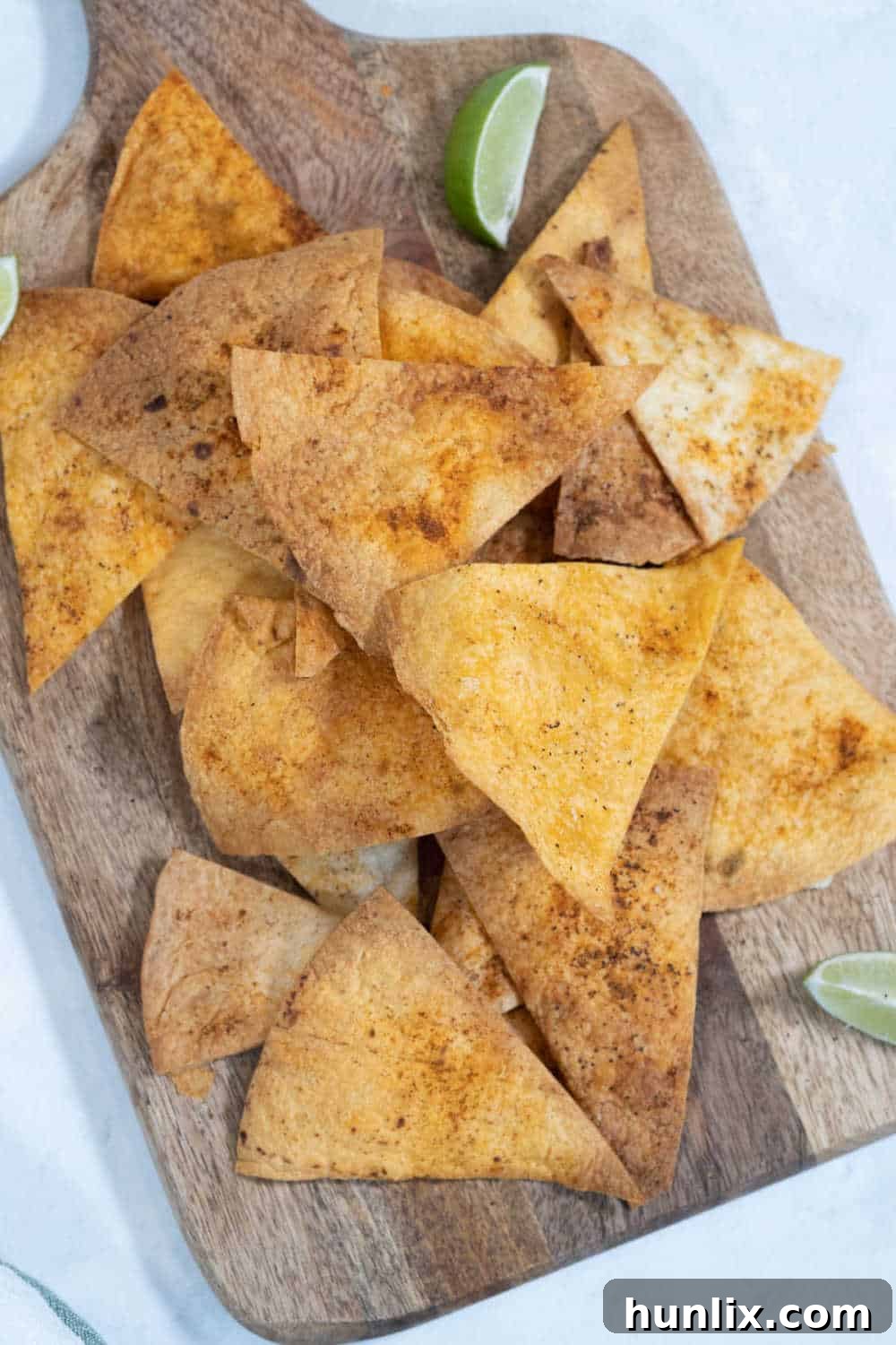 Air fryer tortilla chips arranged on a wooden cutting board, showcasing their golden crispness.