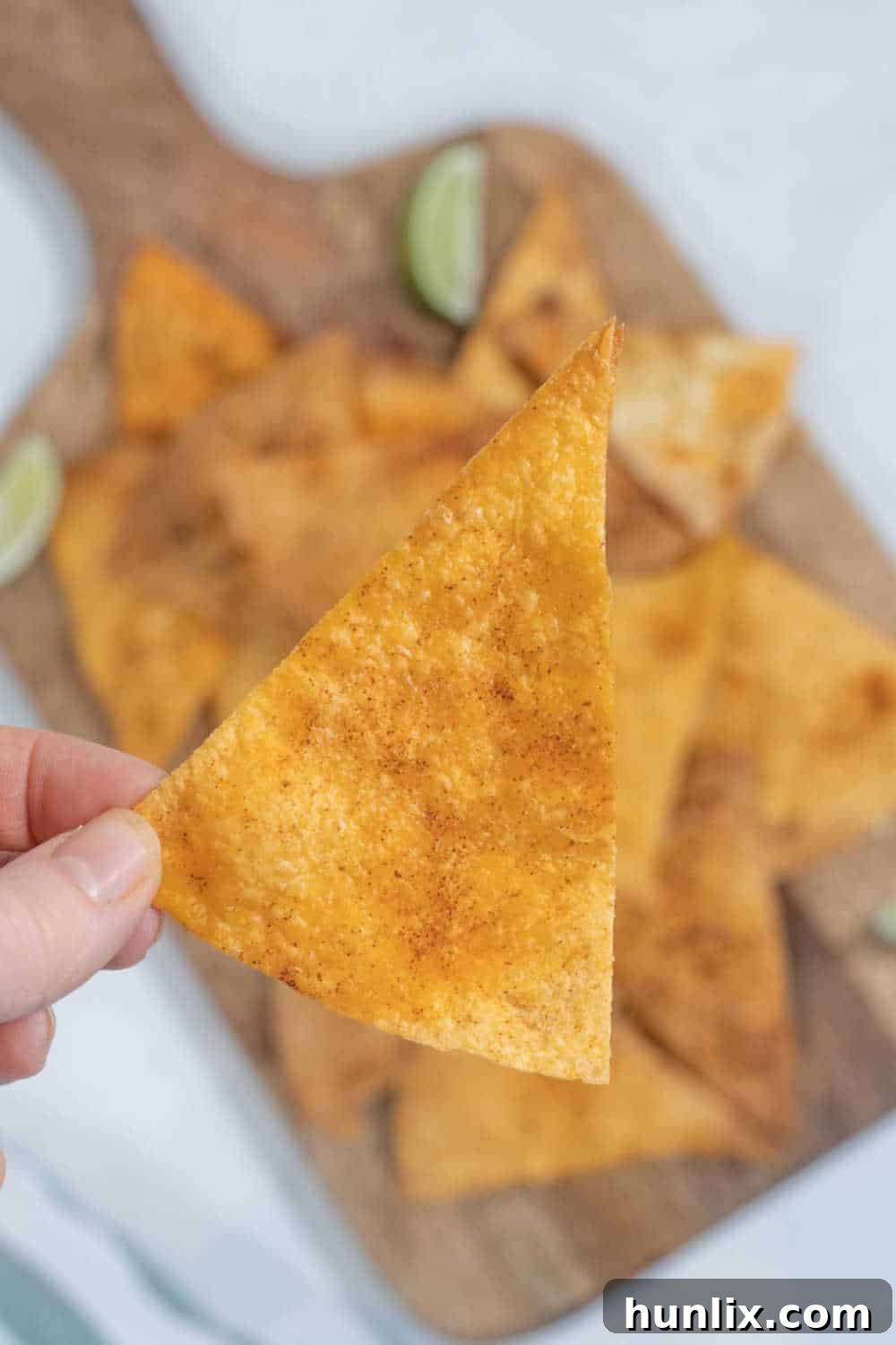 A hand reaching into a pile of air fryer tortilla chips, showing their irresistible crispiness.