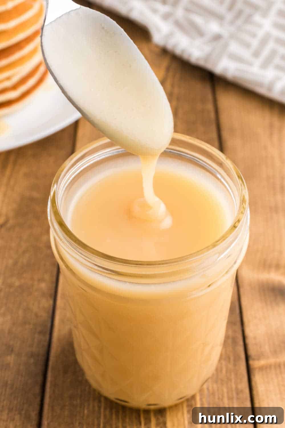 Golden Pancake Drizzle 5 A spoon over a mason jar of syrup.