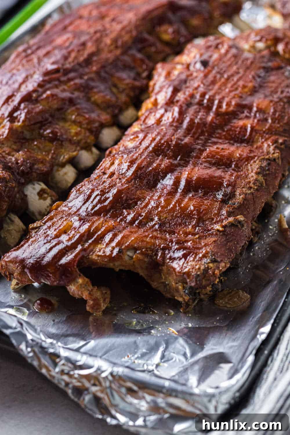 Fall-Off-The-Bone Instant Pot BBQ Ribs 2 BBQ pork ribs on a baking sheet lined with aluminum foil.