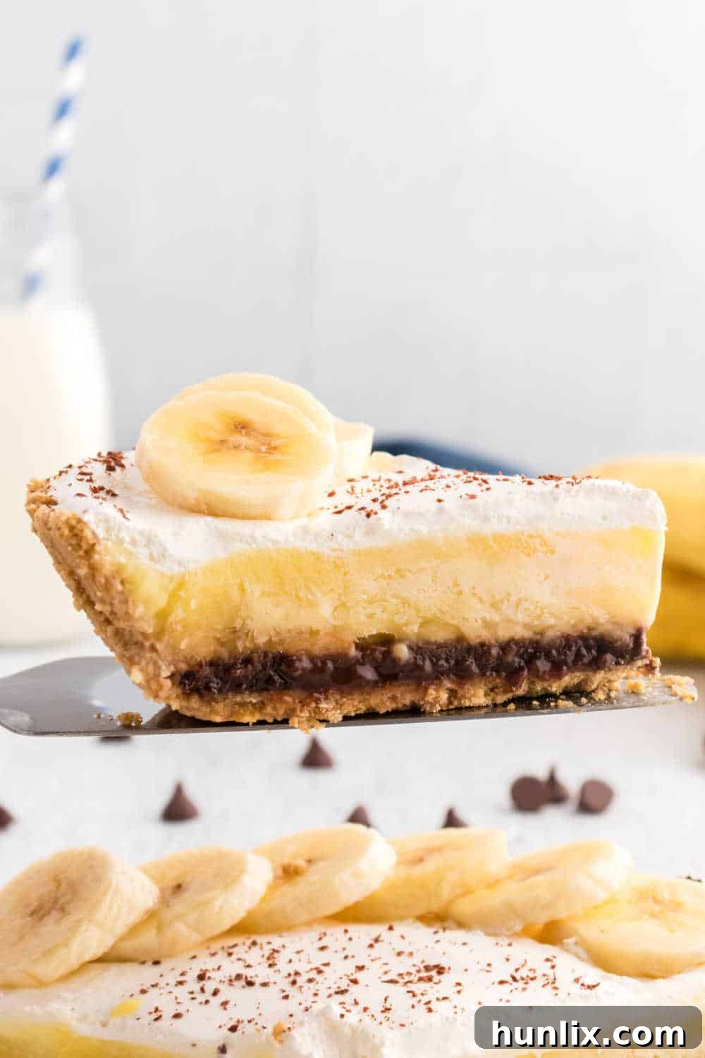 A slice of black bottom banana cream pie on a pie server, ready to be placed on a plate.