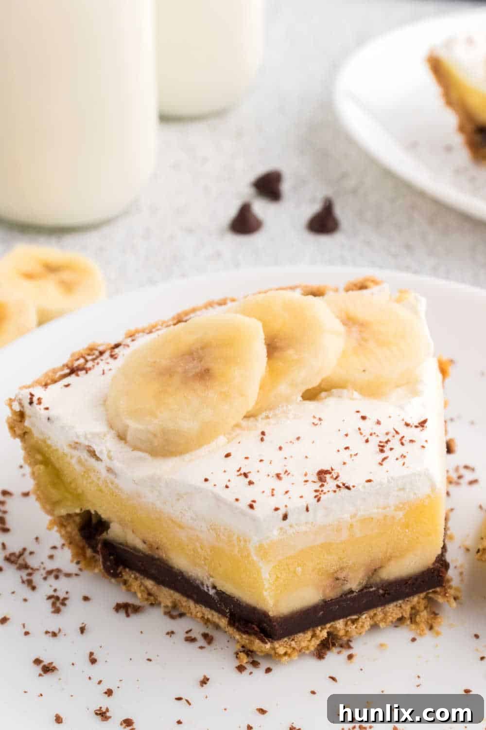A slice of black bottom banana cream pie on a plate, with the end cut off, showcasing the layered texture.