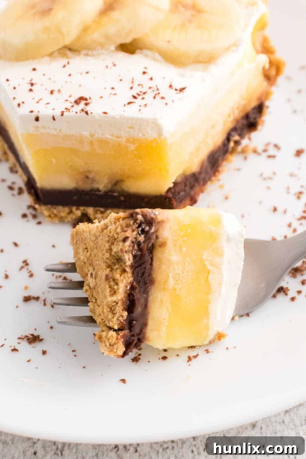 A fork with a bite of black bottom banana cream pie, showing a cross-section of the layers.