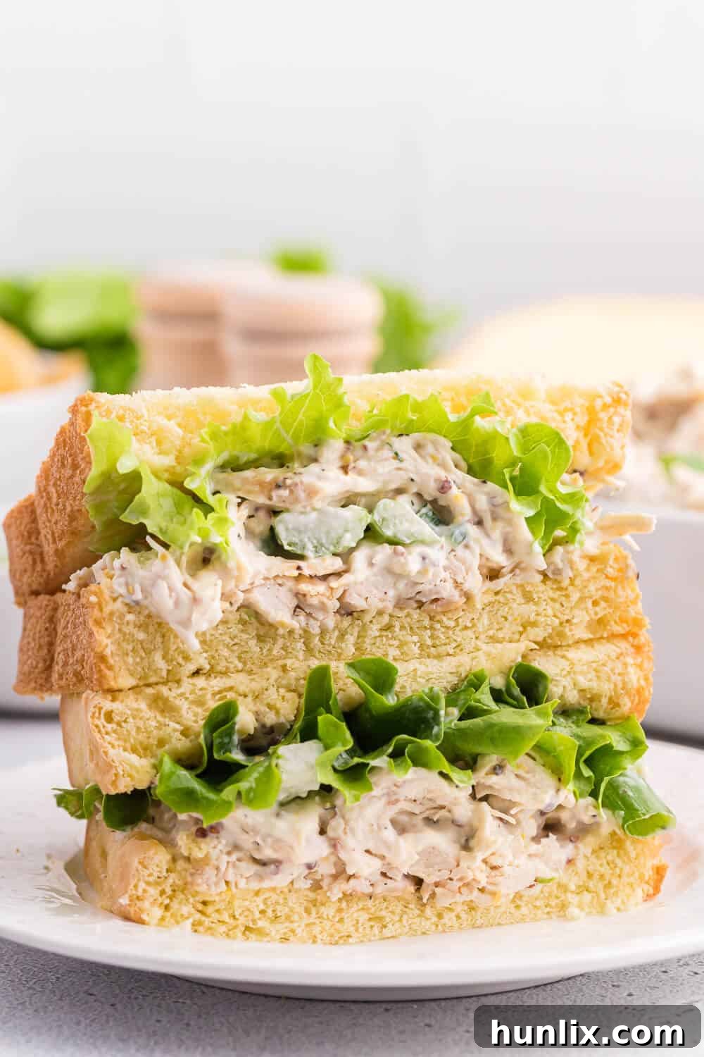 Creamy Homestyle Chicken Salad 9 A stack of delicious chicken salad sandwiches on a white plate.