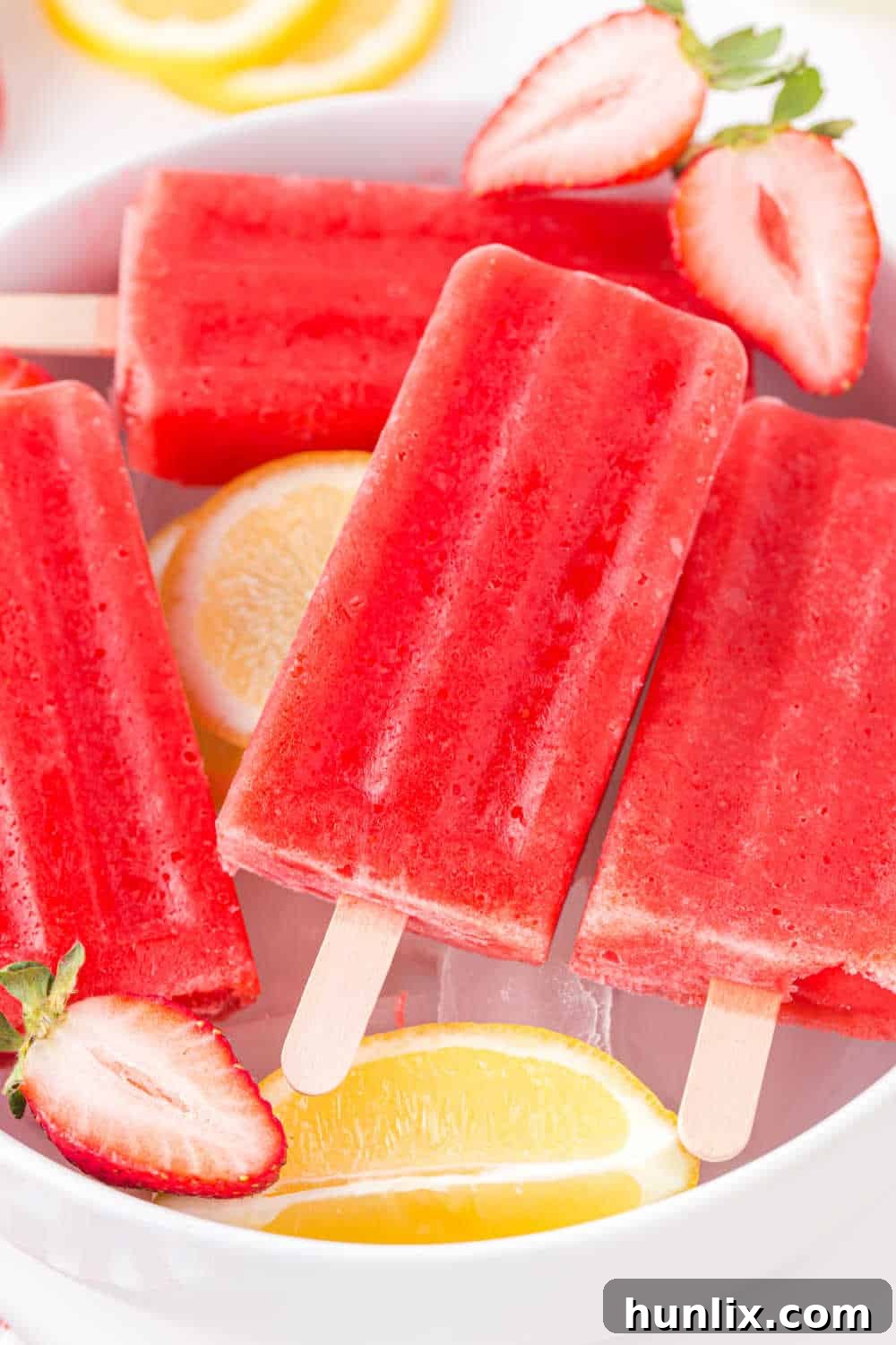 A second shot of strawberry lemonade popsicles presented in a bowl of ice, emphasizing their refreshing appeal.