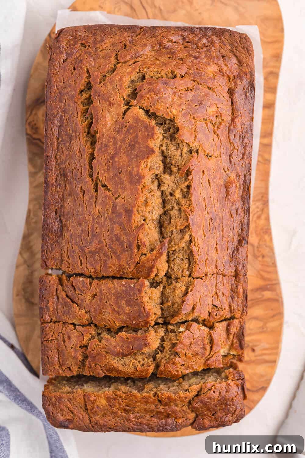 A loaf of banana bread on a wooden surface, perfectly baked and golden brown.