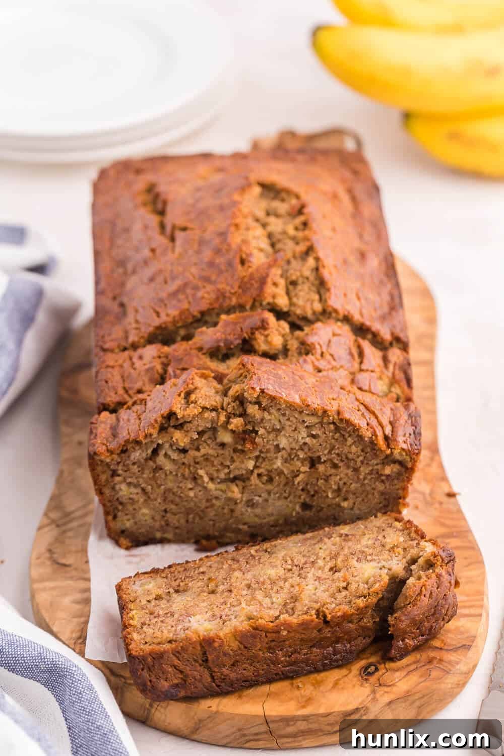 A perfectly baked loaf of banana bread with slices, ready to be eaten.