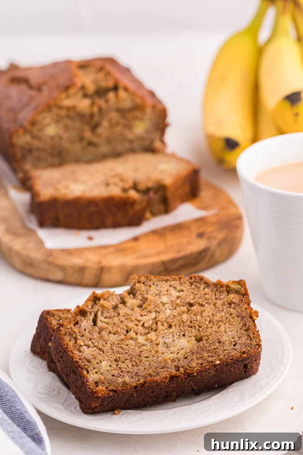 A slice of banana bread on a small white plate, ready to be eaten.