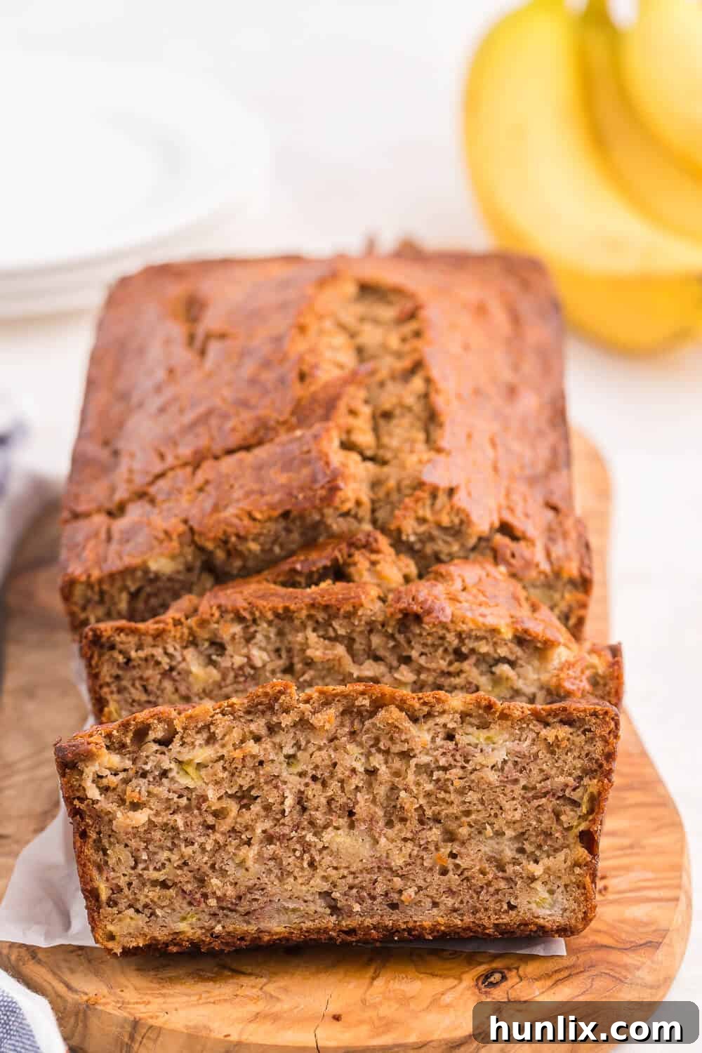 A loaf of banana bread with several slices cut at the end, showing its moist interior.