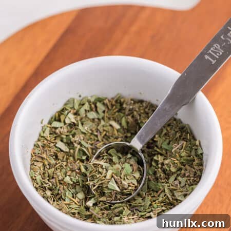 Italian seasoning in a bowl with a measuring spoon.