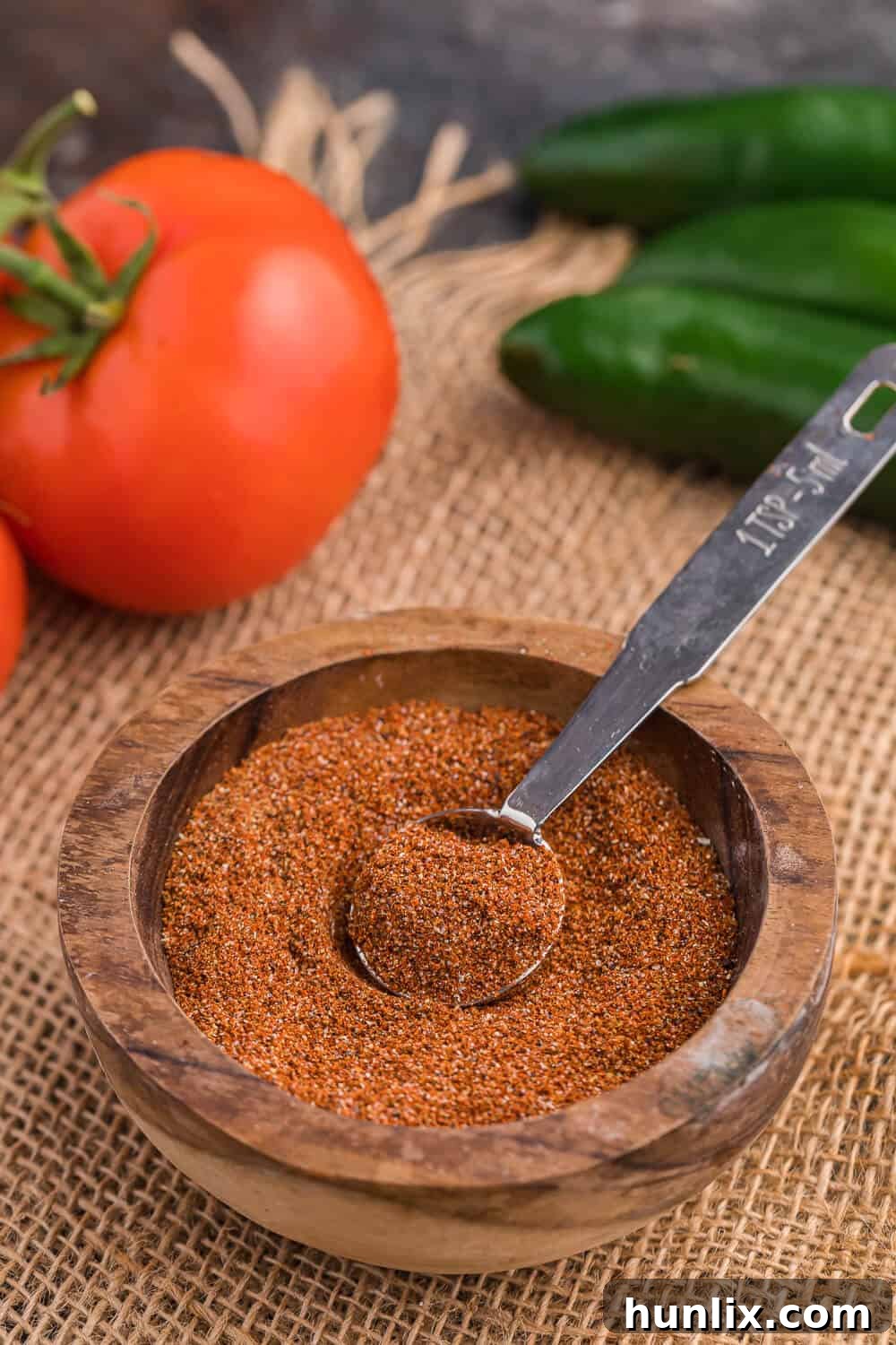 A wooden bowl with homemade taco seasoning and a measuring spoon, showcasing rich colors.