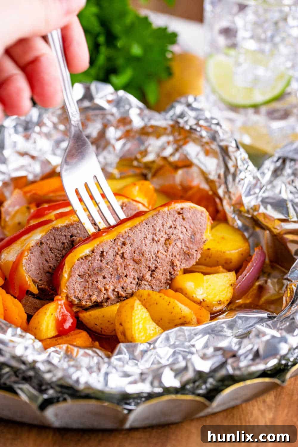 Fireside Burger Pockets 9 A burger in a hobo packet cut in half with a fork in it.