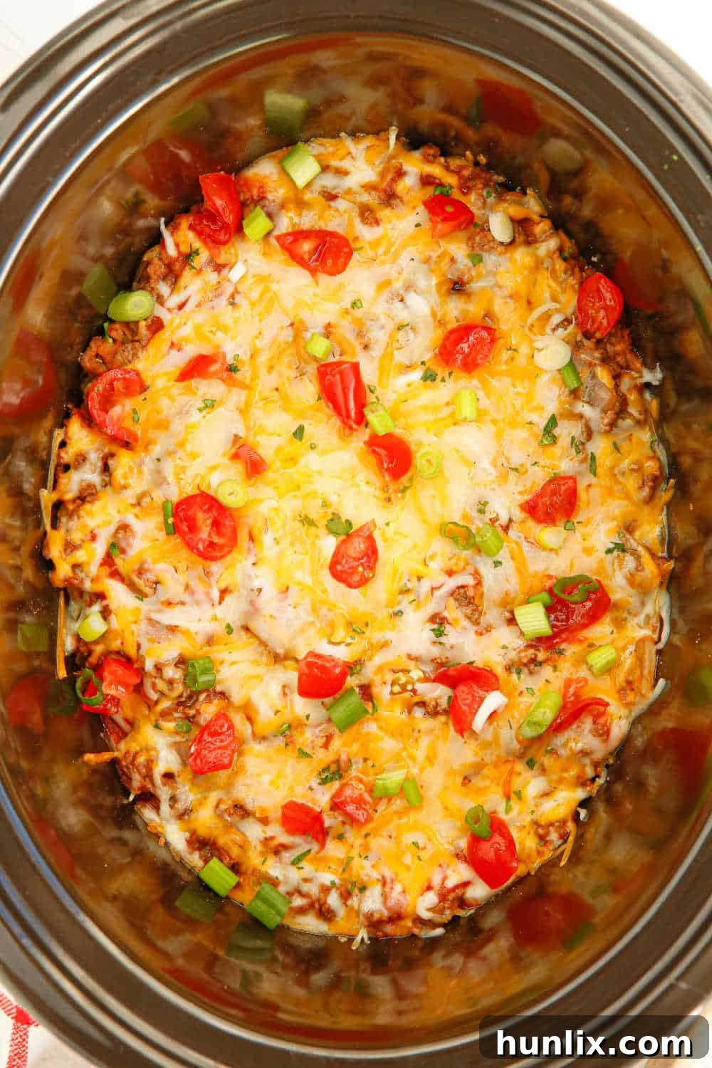 Fall-Apart Beef Enchilada Slow Cooker Supper 2 A bubbling slow cooker filled with golden-brown beef enchilada casserole, topped with melted cheese and ready to serve.
