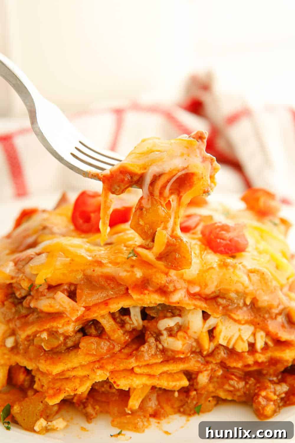 Fall-Apart Beef Enchilada Slow Cooker Supper 10 A fork holding a bite-sized piece of slow cooker beef enchilada casserole, showing the juicy beef, melted cheese, and tender tortilla, inviting a taste.