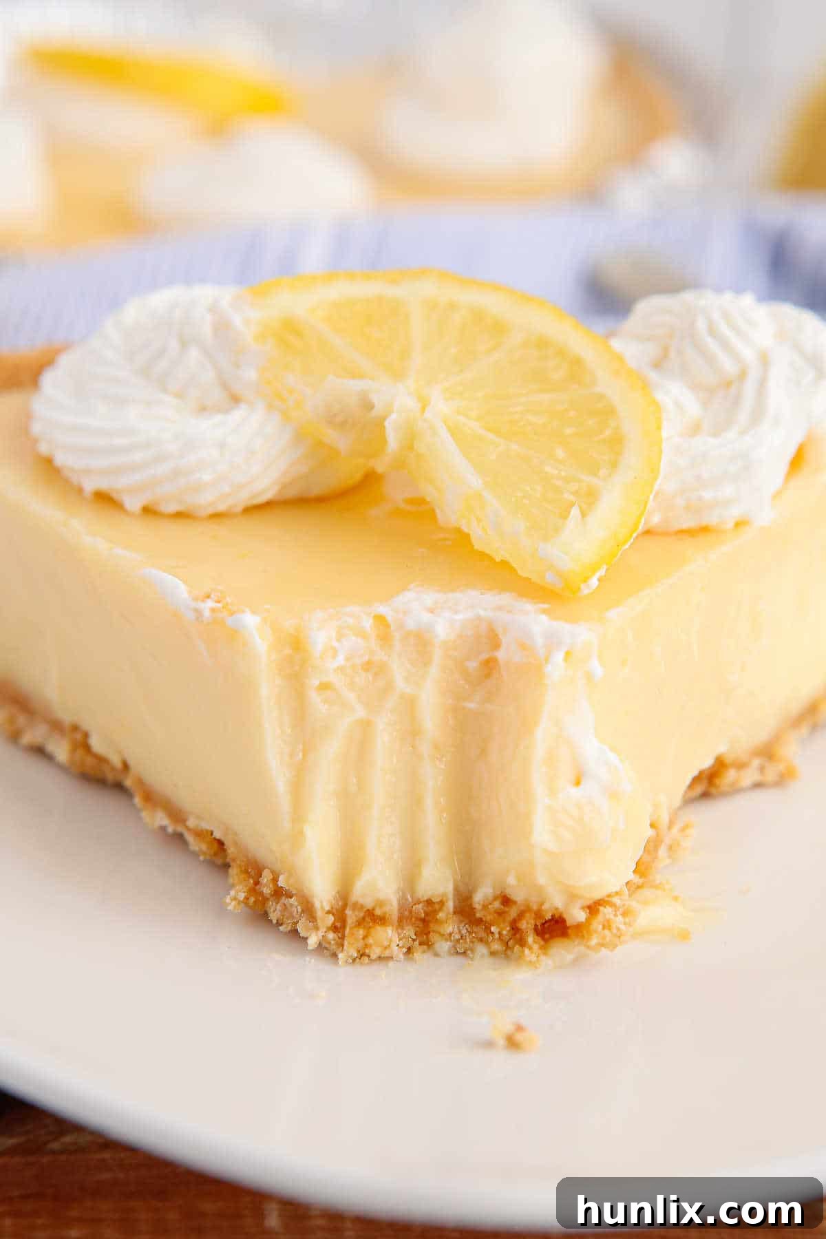 Classic lemon pie slice on a plate with a bite off the tip.