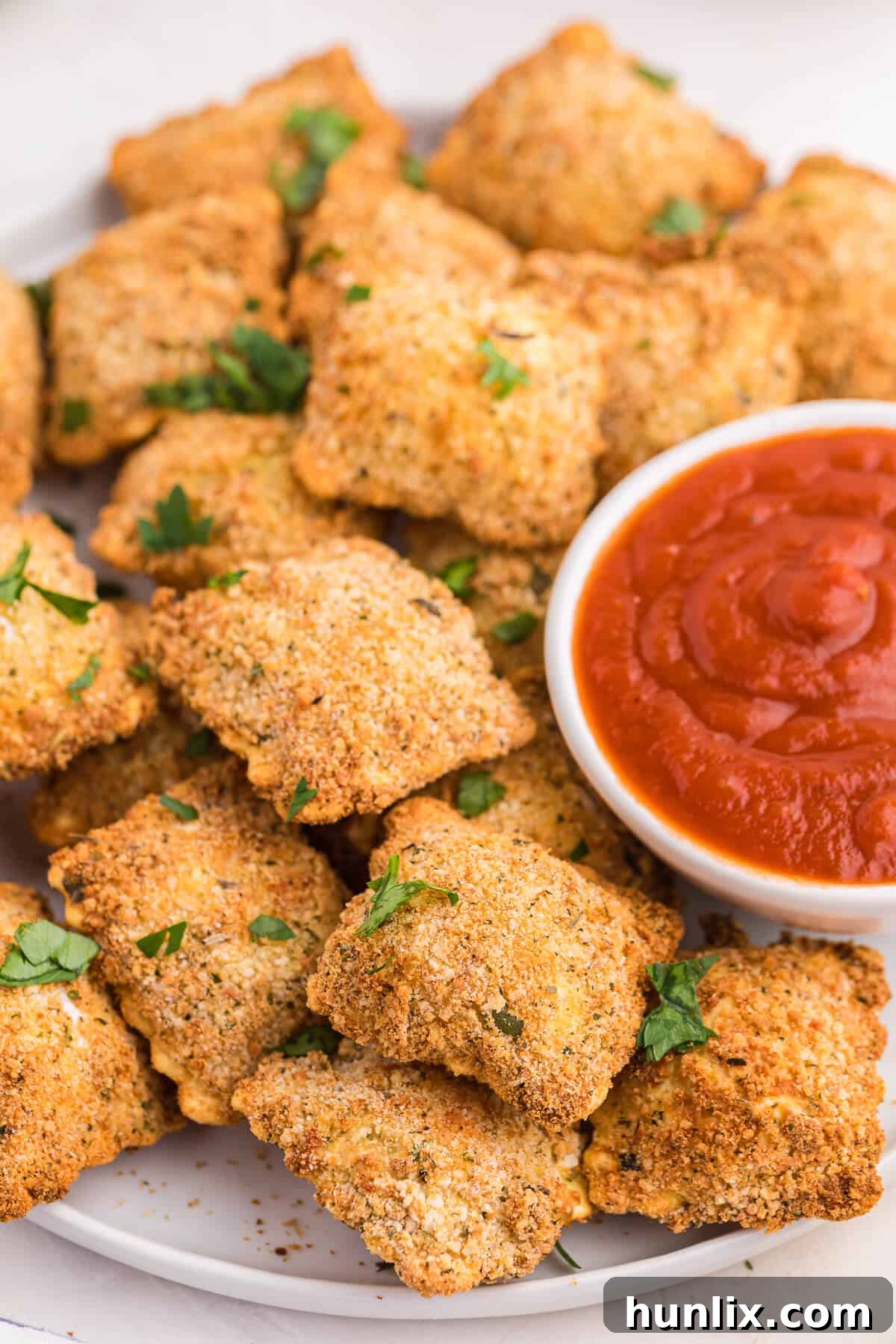 Golden Air Fryer Ravioli 8 The recipe served on a plate with marinara sauce.