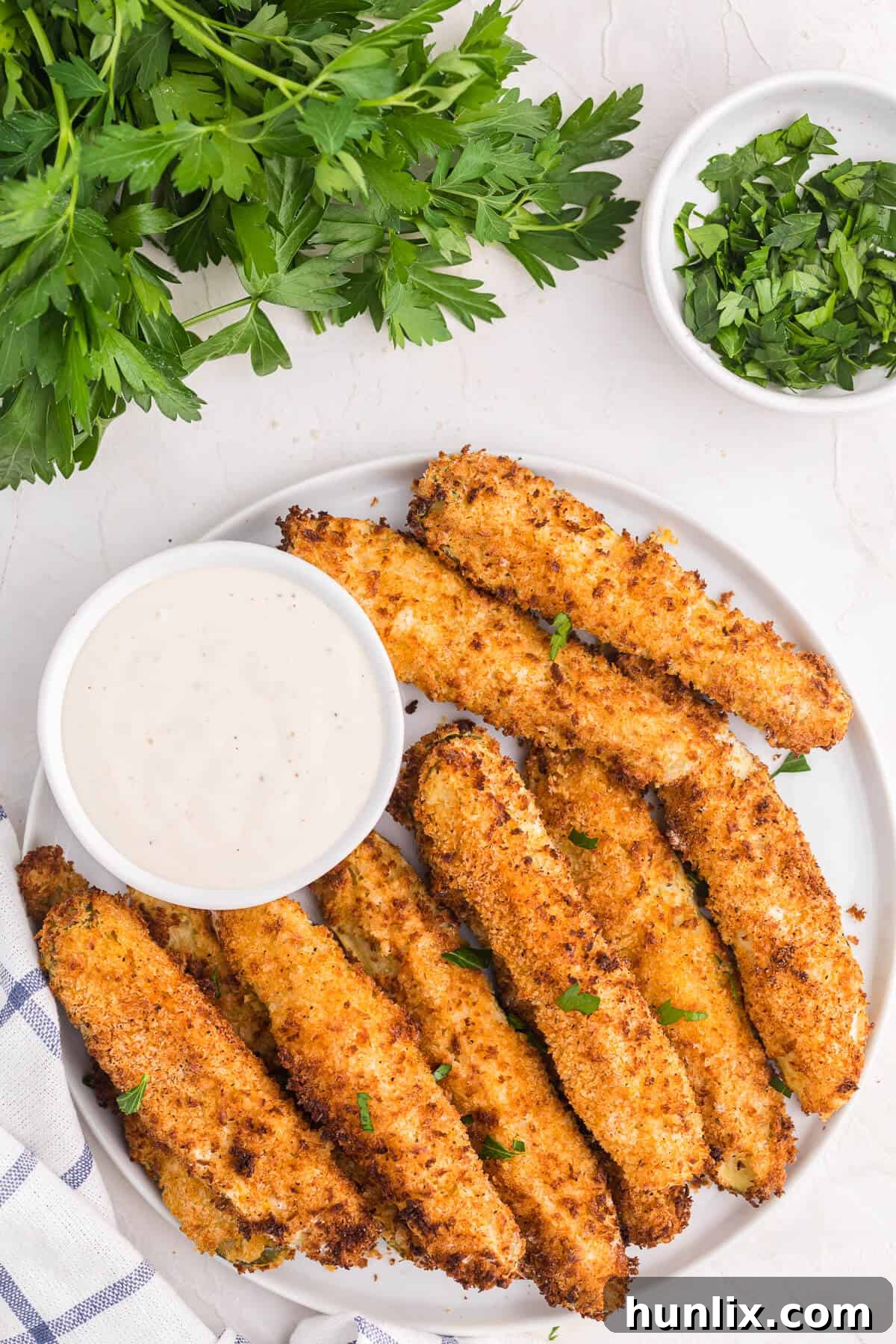 A plate of golden-brown air fryer fried pickles with a side of creamy ranch dressing, ready to be enjoyed as a crispy game-day snack.