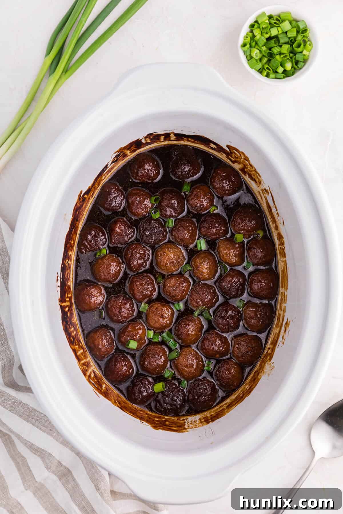 Grape-Glazed Meatballs 2 Grape jelly meatballs in a white crockpot.