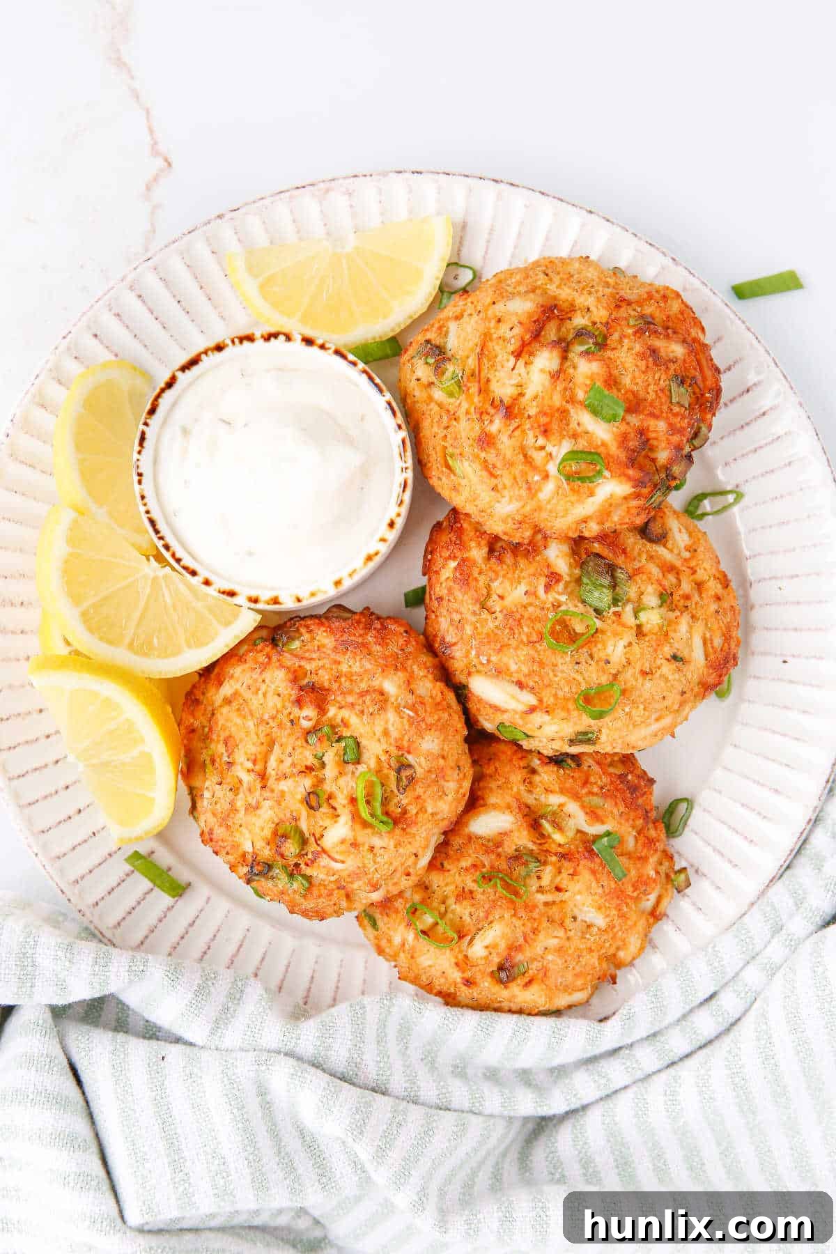 Perfectly Crispy Air-Fried Crab Cakes 6 Beautifully cooked Air Fryer Crab Cakes served on a plate with fresh lemon wedges and a side of creamy tartar sauce.